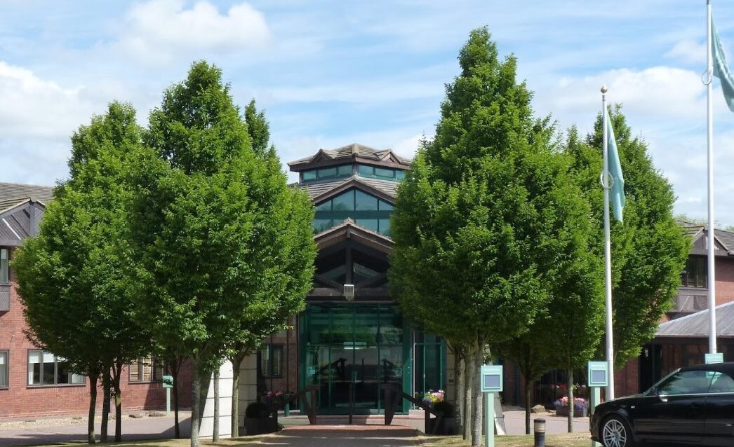 Glass entrance to building with large trees in front of it (Staverton Hotel Daventry)