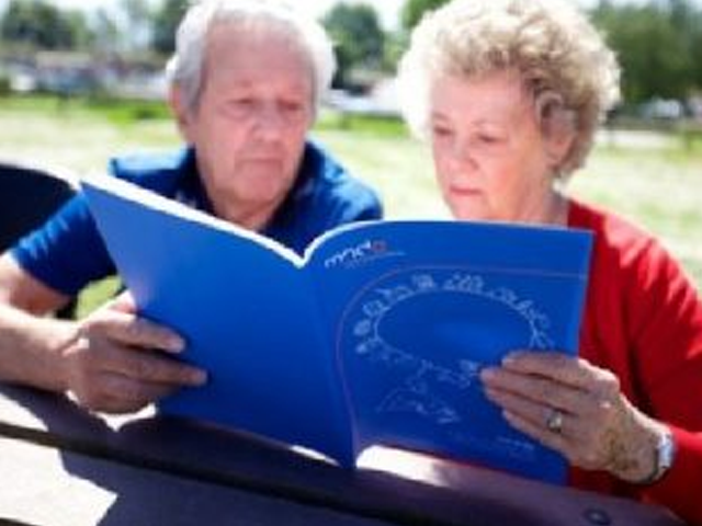Two people reading information booklet in a sunny park