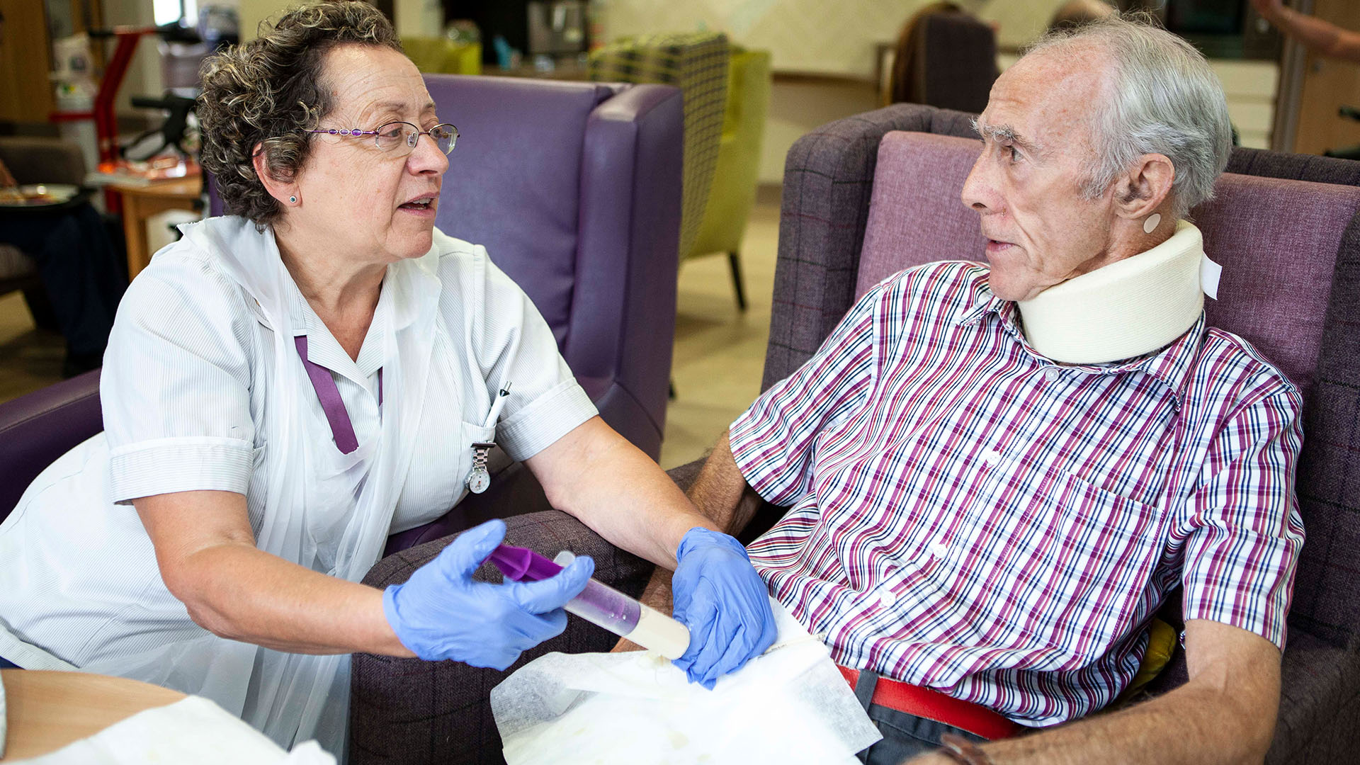 A health professional administering a PEG feed to a man