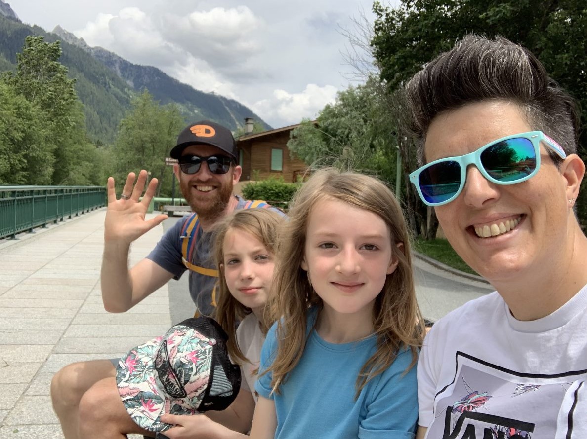 Alex and his family in front of a mountain covered in trees