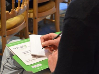 A person at an education event taking notes