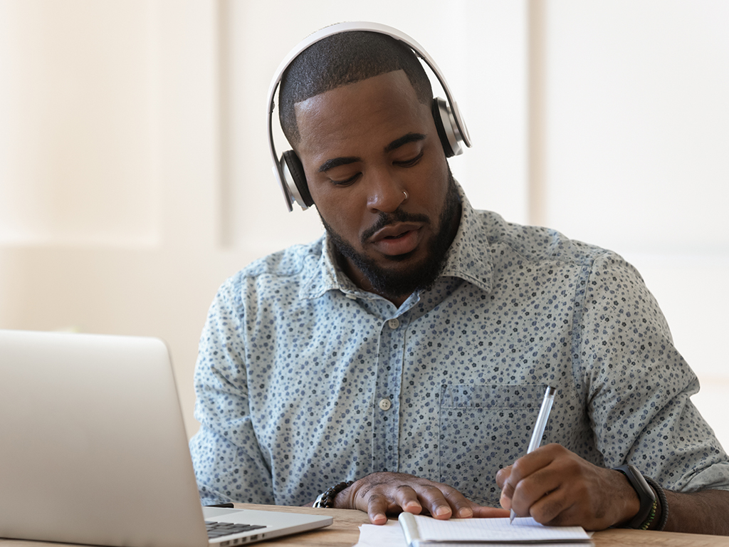 Man wearing a headset making notes