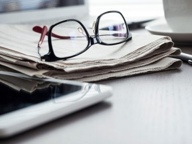 a pair of reading glasses sitting on top of a newspaper