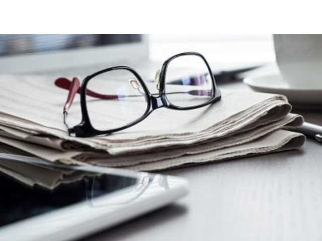 a pair of reading glasses sitting on top of a newspaper