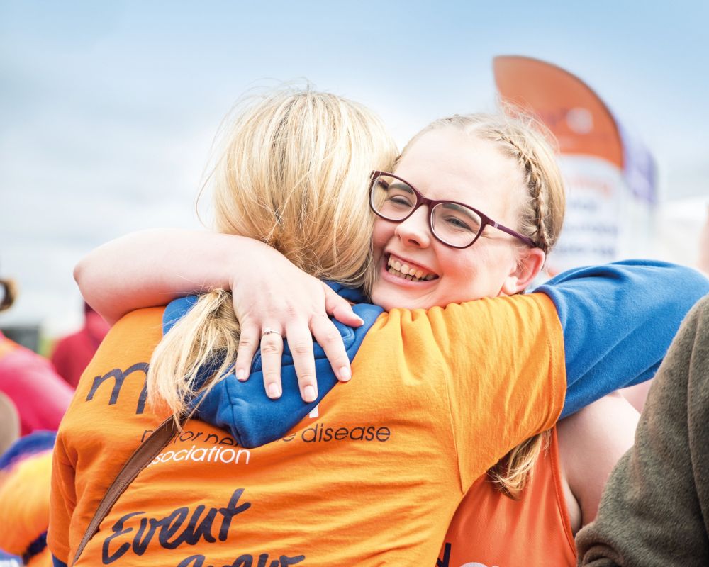 MND supporter hugging a MND volunteer at the finish line of a running event