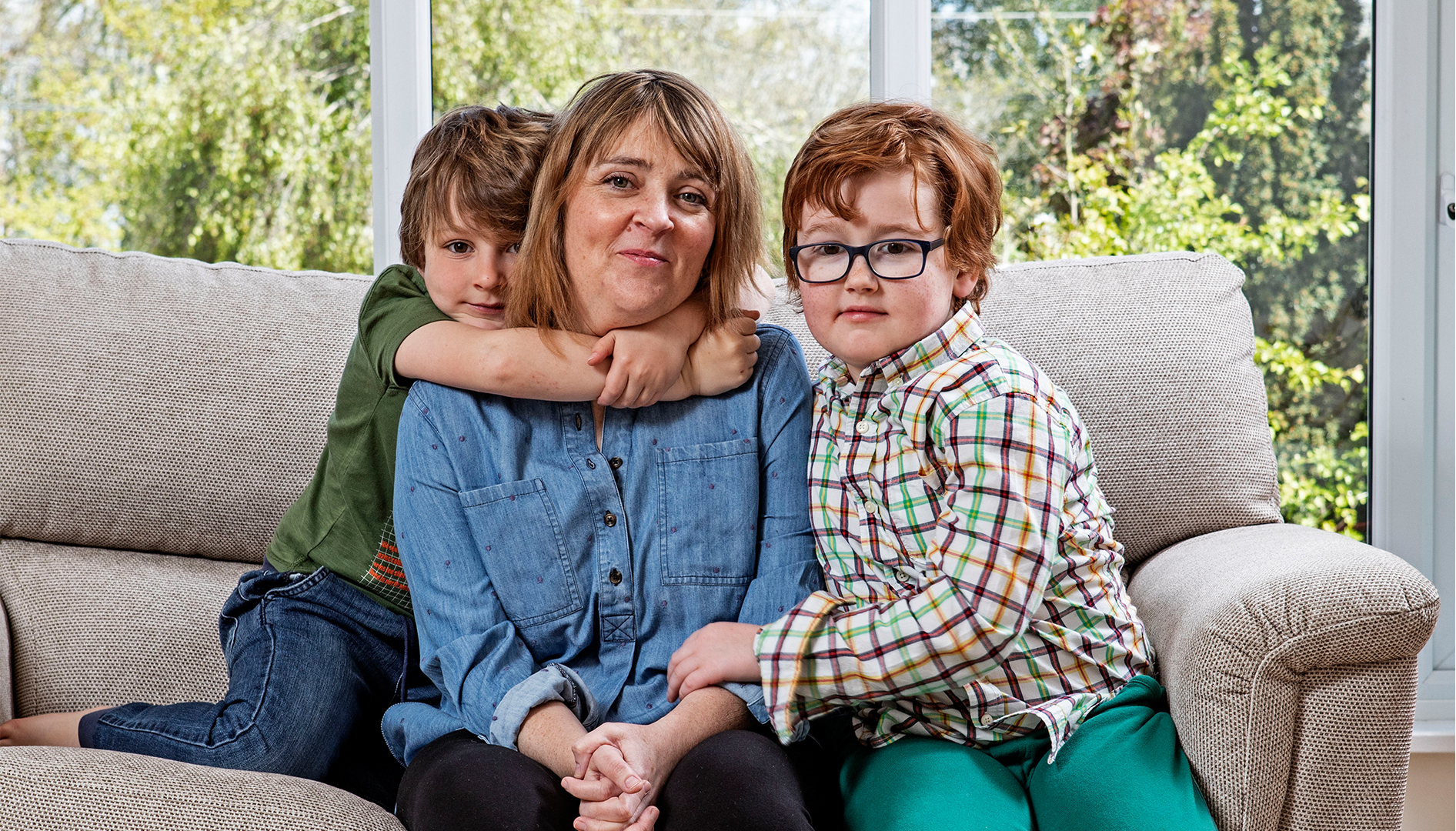 mother and children sitting on sofa looking to camera