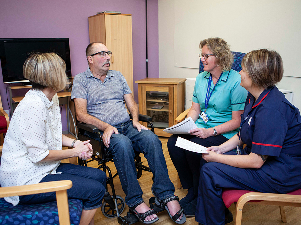A group of professionals from different disciplines talking to a person with MND