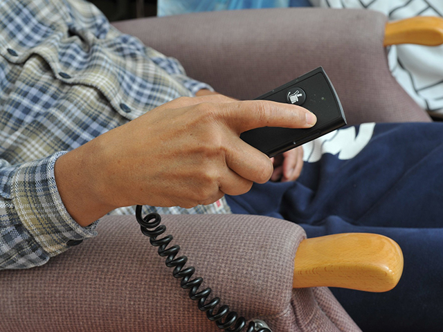 A person using the remote control of a riser recliner chair