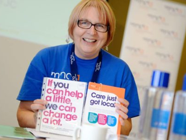 a person holding MNDA information booklets 