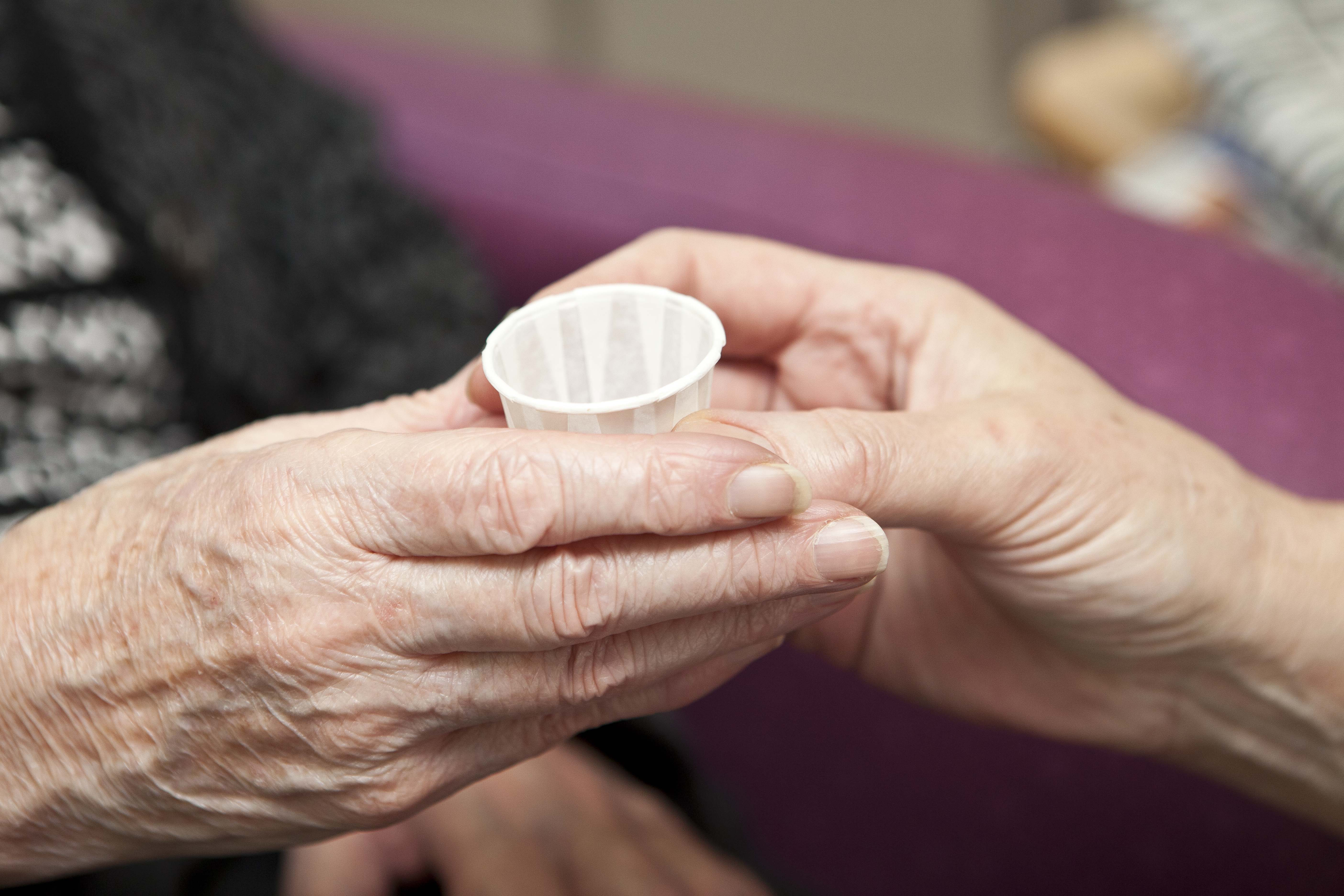 two hands passing medication in a cup