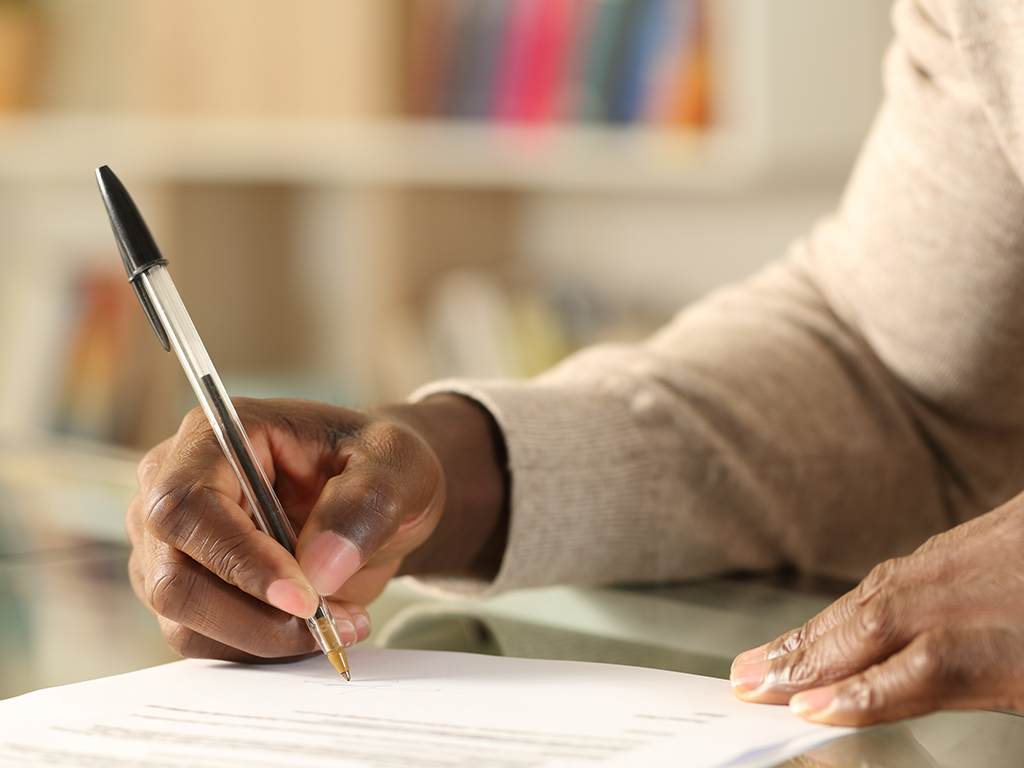 person holding pen completing forms 