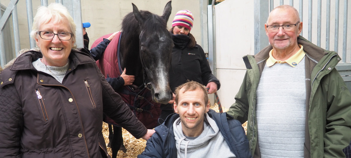 a photo of rob burrow and family in a horse stable