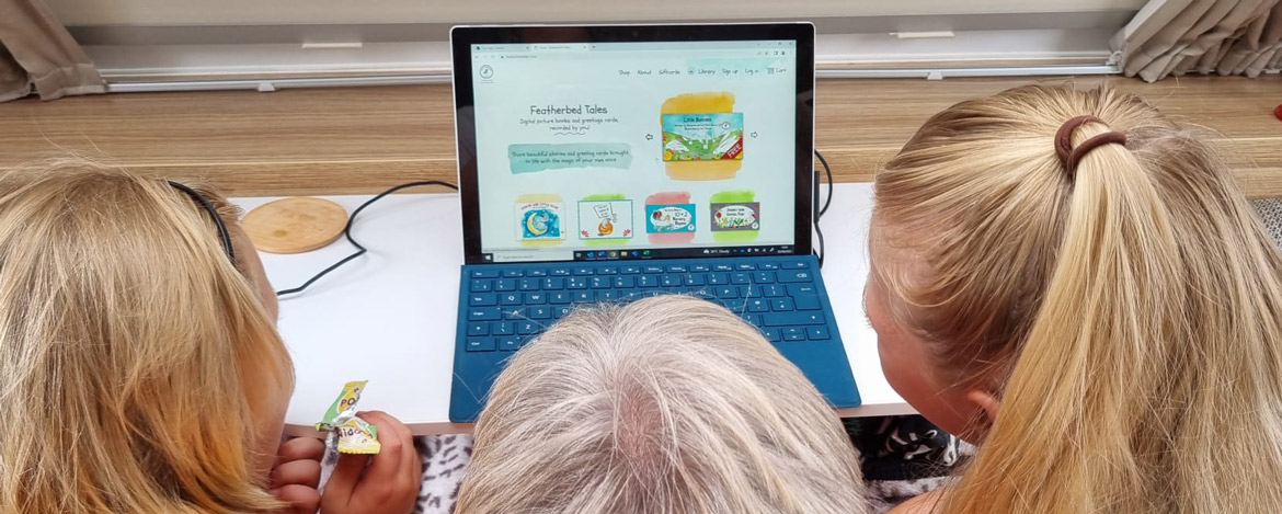 Children around a computer using the FeatherBed tales voice banking technology