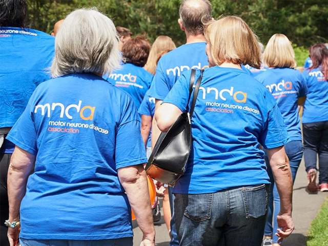 a group of people walking wearing mnda t-shirts