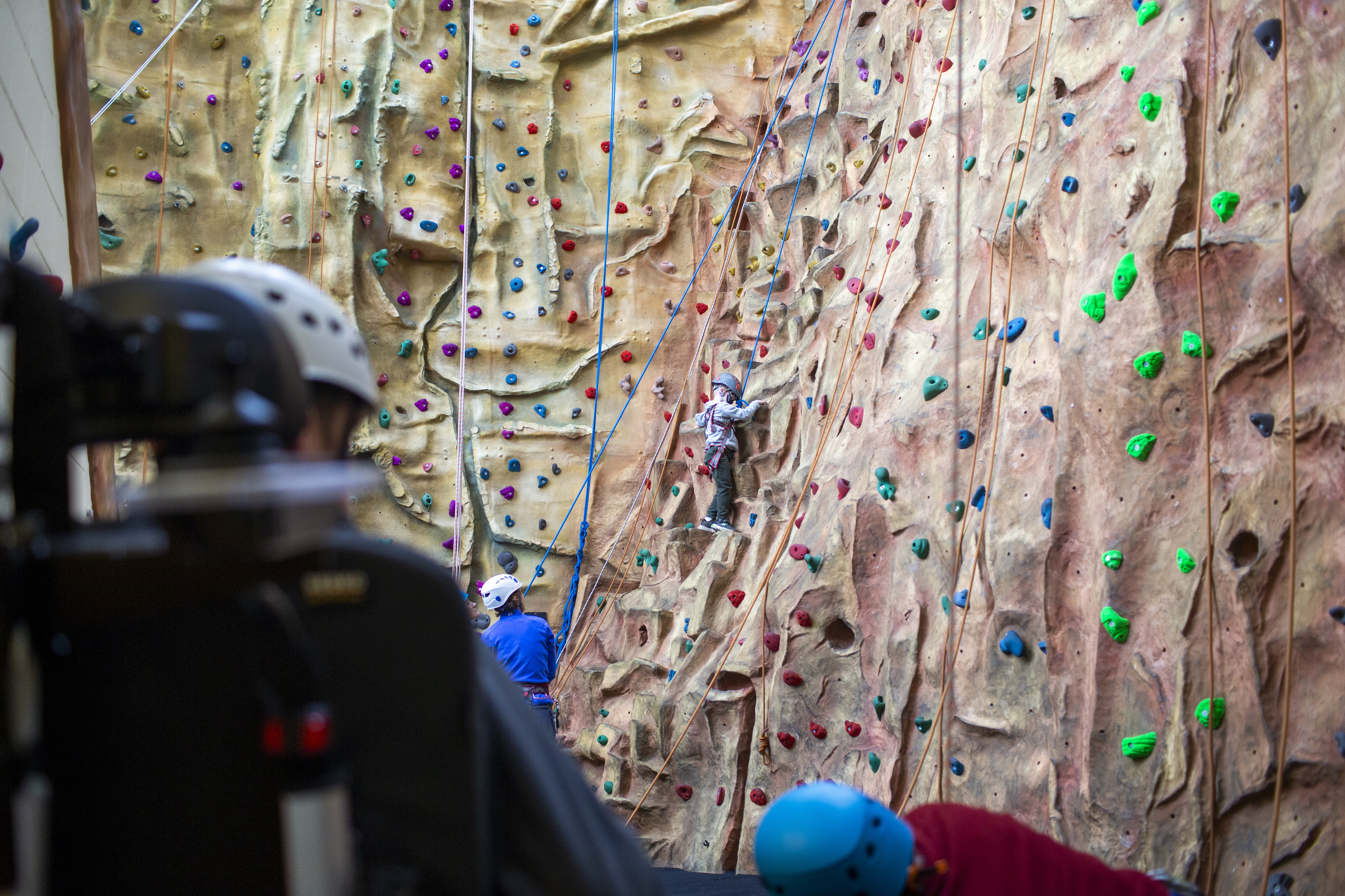 A large rock climbing wall that a child is scaling