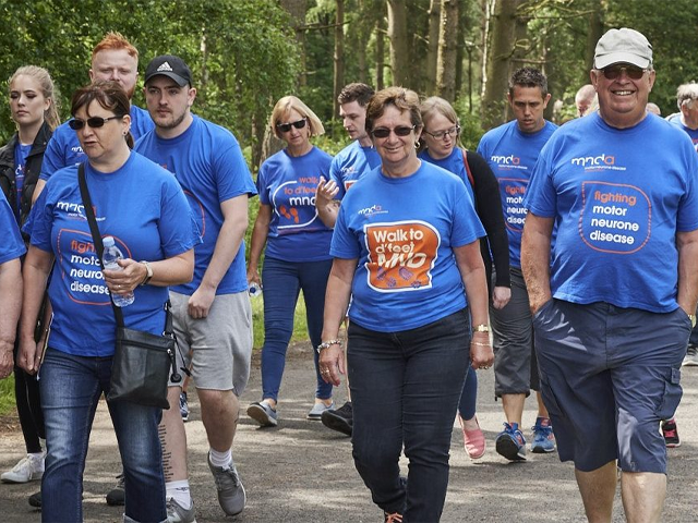 a group of people walking wearing mnda t-shirts