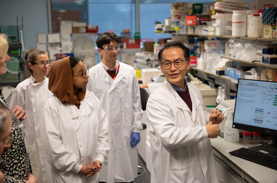 Four researchers in a laboratory sharing information with visitors out of picture