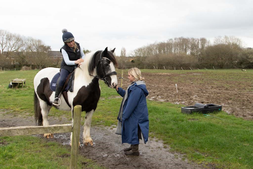Nickie on her horse with her daughter Ellie stroking the horse