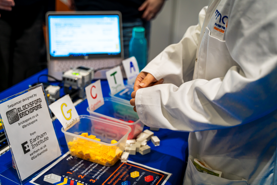 Someone taking lego bricks from boxes in front of the lego gene sequencer