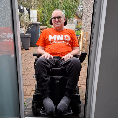 Liam is using his ramp on his back door. He is returning to the house in his wheelchair, wearing an MND Association tshirt.