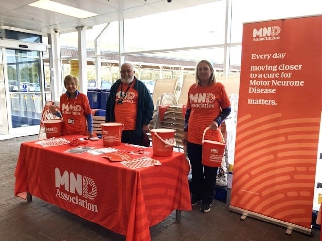 Volunteers smiling at a stand with buckets