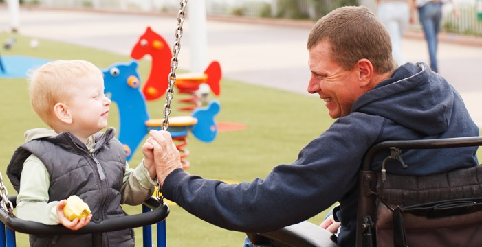 Father in wheelchair with young child on a swing