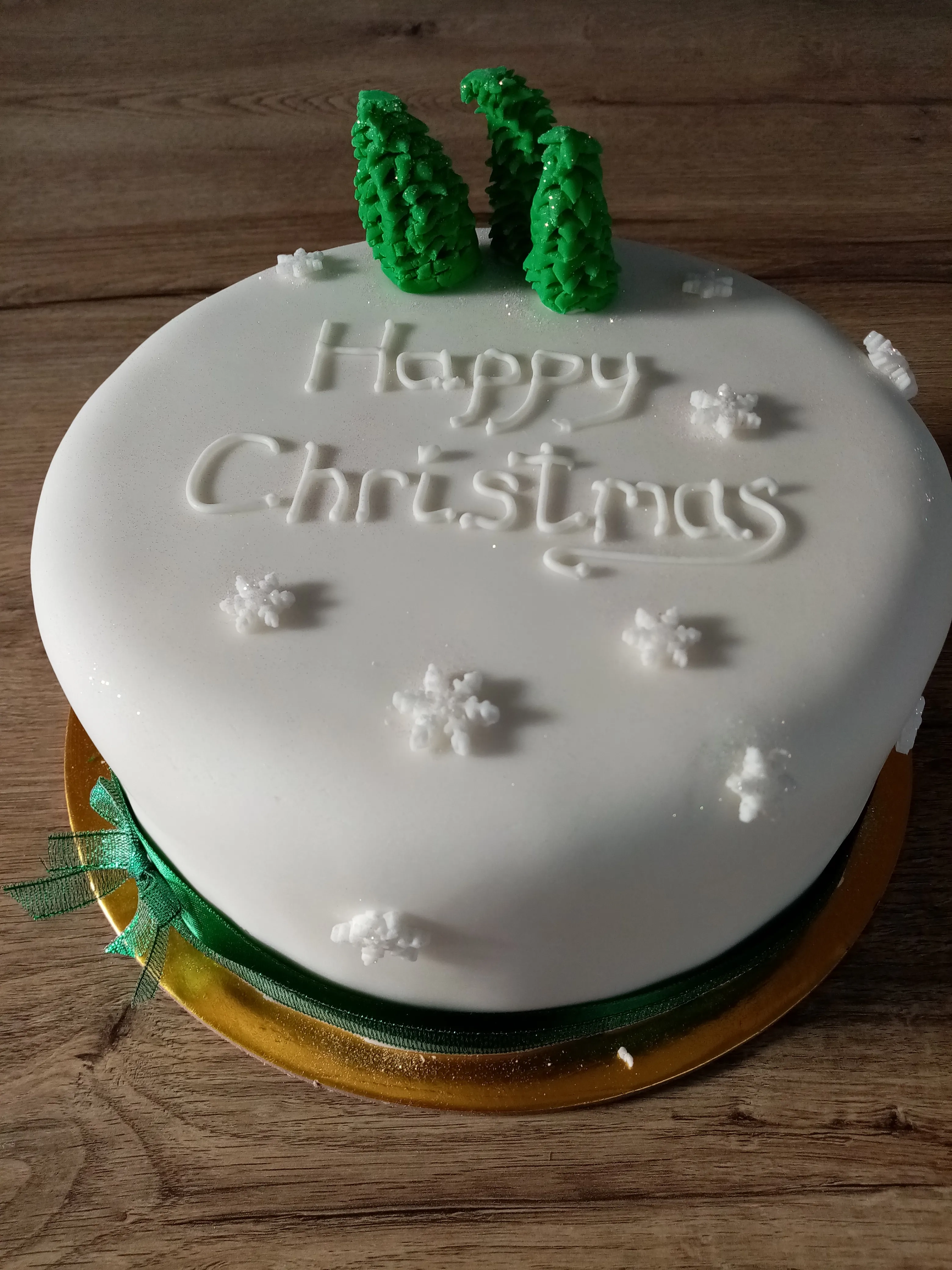A Christmas cake with happy Christmas written in icing on top of it