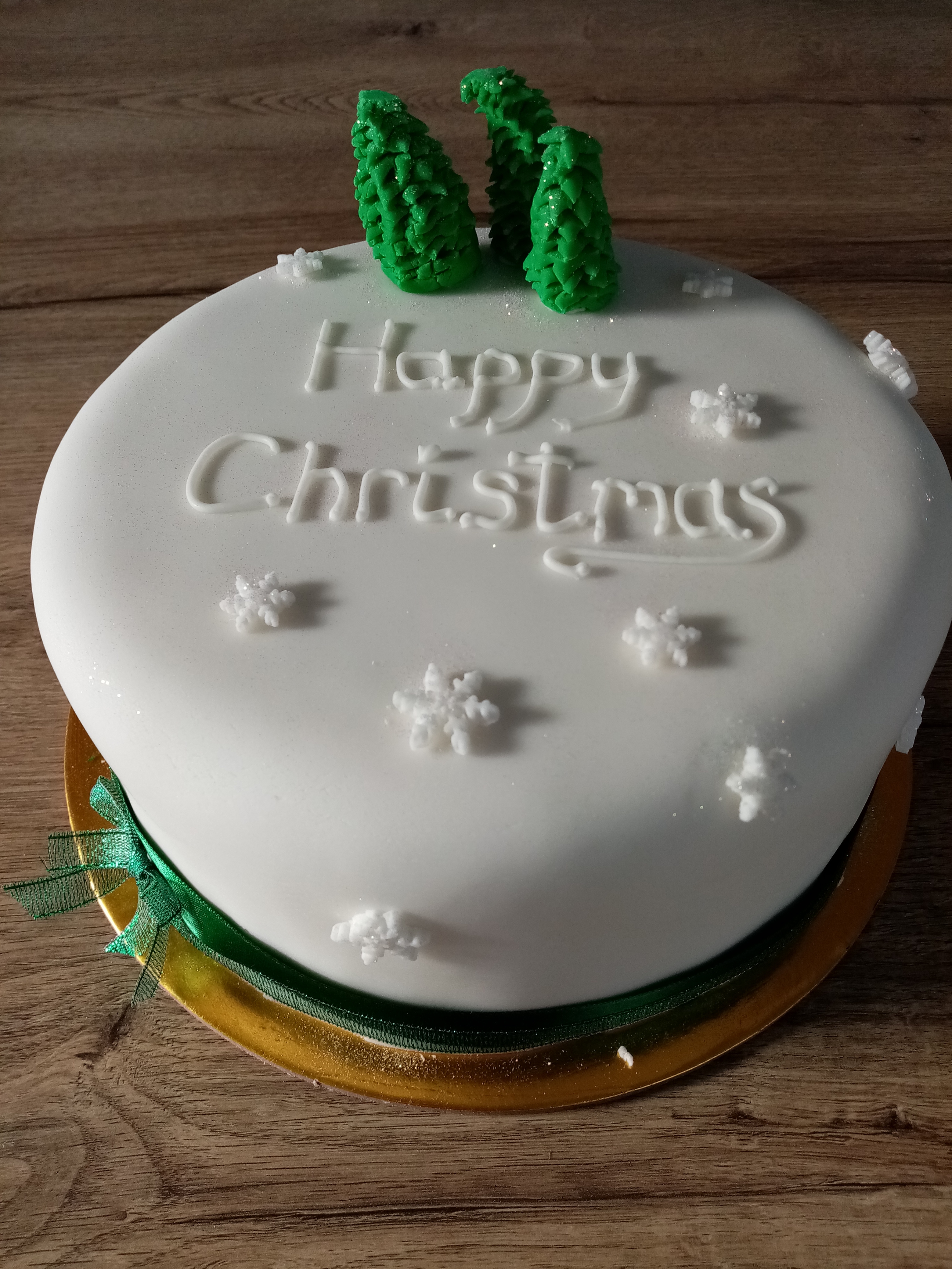 A Christmas cake with happy Christmas written in icing on top of it