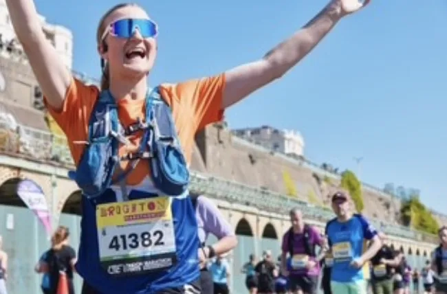 Molly running with her arms in the air at the Brighton Marathon