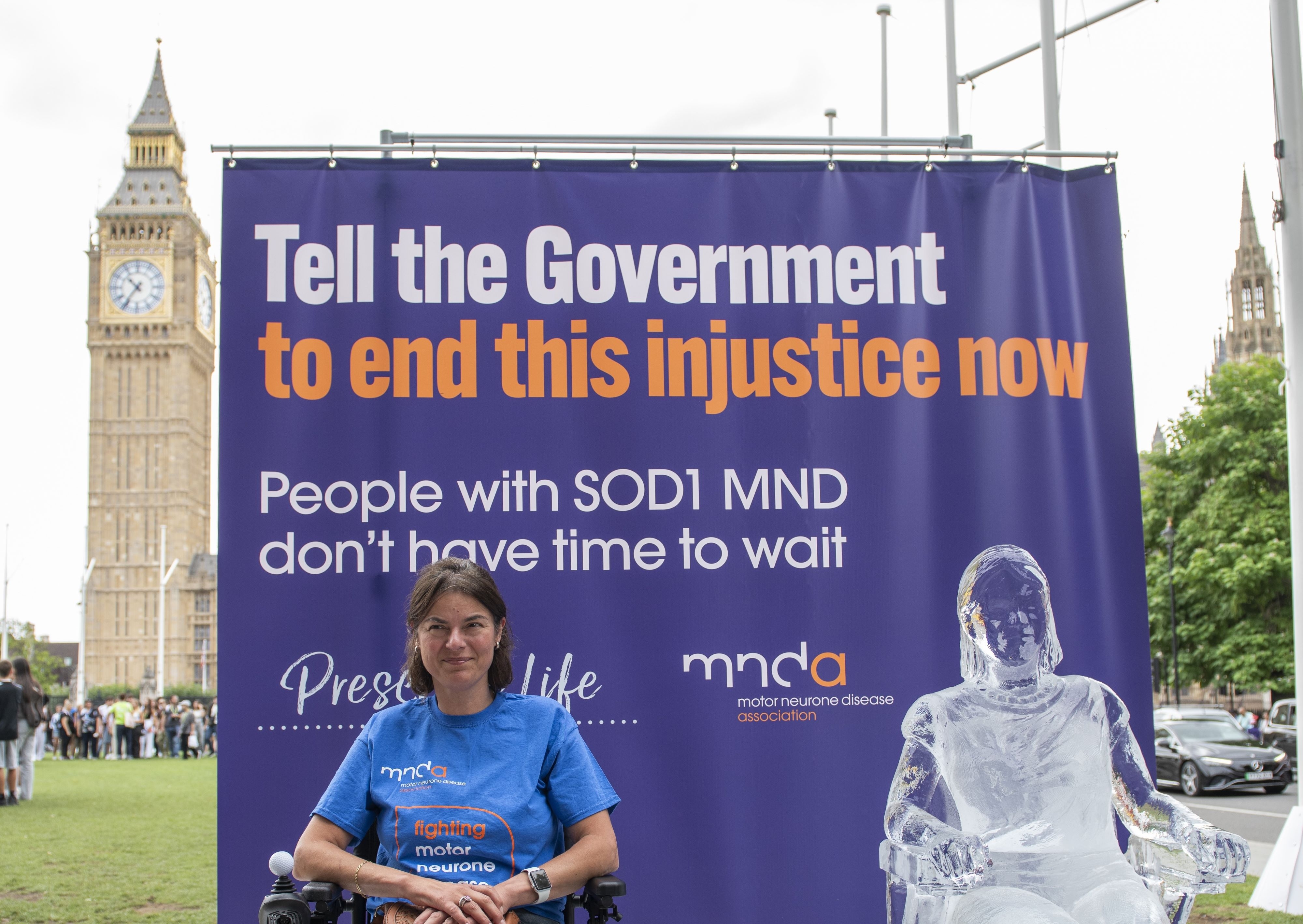 Seckin McGuirk, who has SOD1 MND, sits next to an ice sculpture modelled on her. Big Ben is in the background.