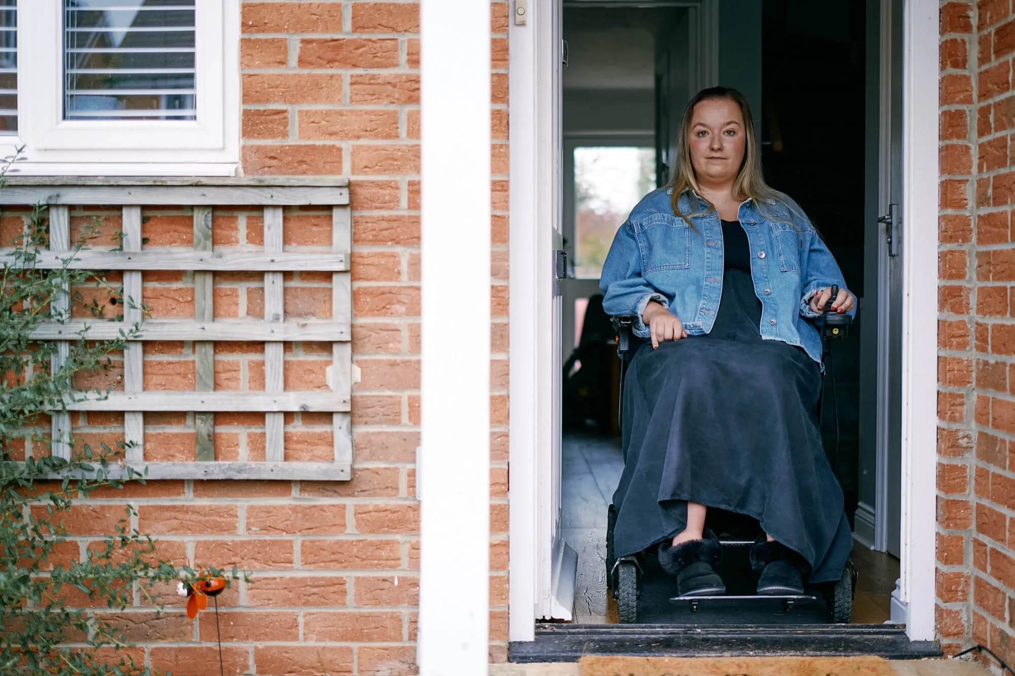 Charlotte in her wheelchair looking out of the front door of her house.