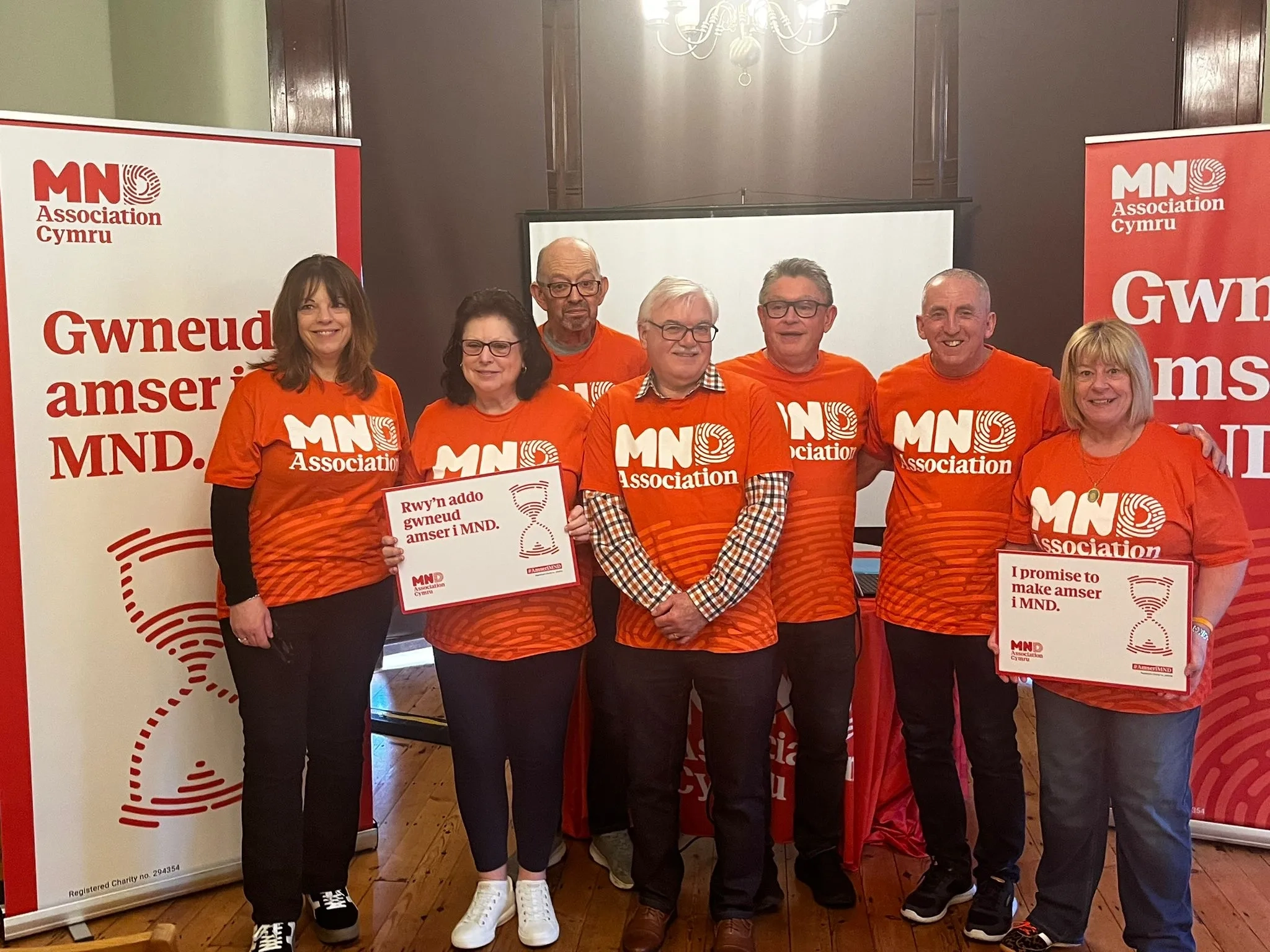 A group of MND Association campaigners stand with MND Association roller banners.