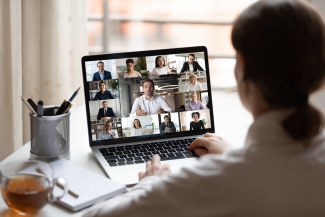 person in front of the laptop attending an online meeting with multiple people