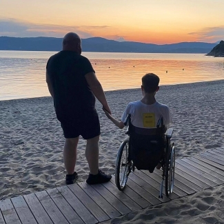 Alex and Craig - holding hands on the beach looking out at a sunset