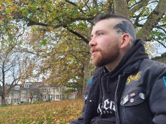 Patrick sitting outside - autumnal trees in the background 