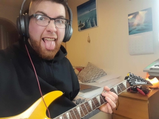 Patrick pulls a silly face whilst holding his guitar