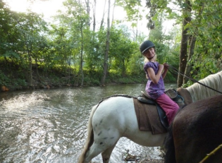 Martin's daughter, Martha, rides a horse outside in the woods