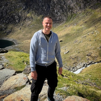 James outside walking, smiling at camera