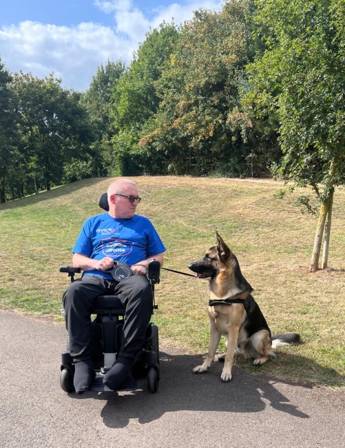 Liam - in his power chair - with his dog at the park. Looking at each other.