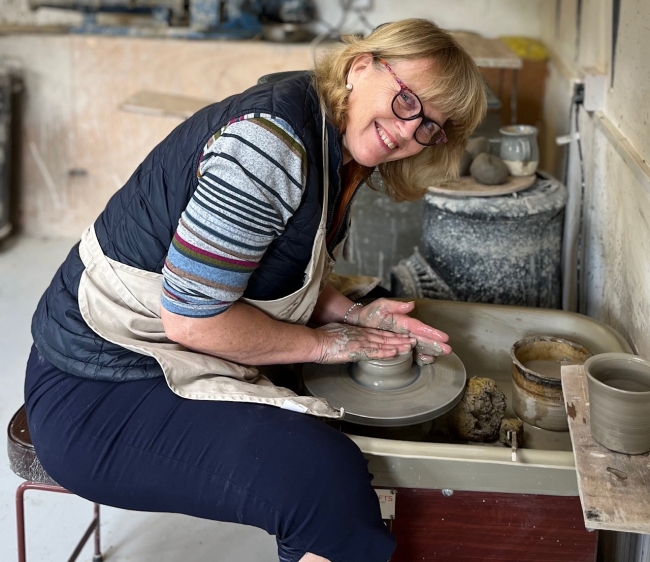 Linda sitting at the pottery wheel, smiling