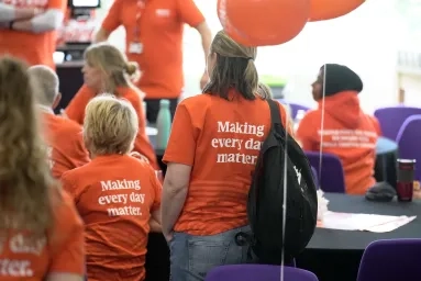 A group of volunteers listening to a talk at an event.
