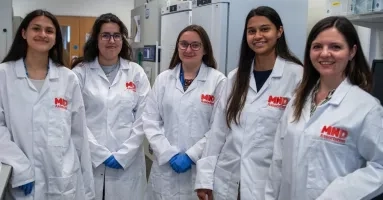 A group of scientists in a lab wearing MND association lab coats.