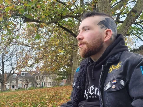 Patrick looking away from the camera surrounded by nature 