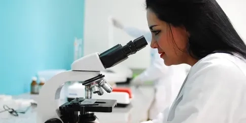 Researcher in a lab looking down a microscope