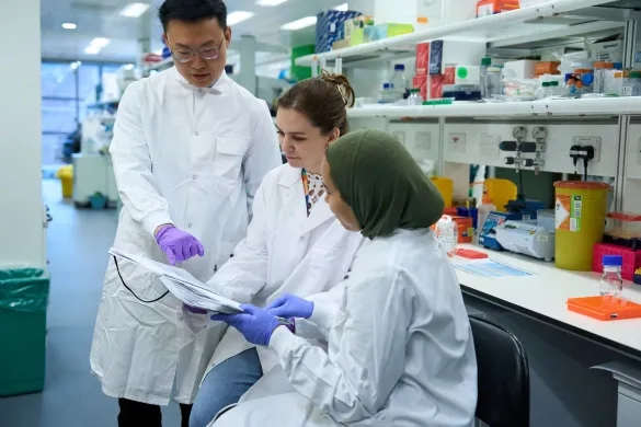 Three researchers in white lab coats having a discussion
