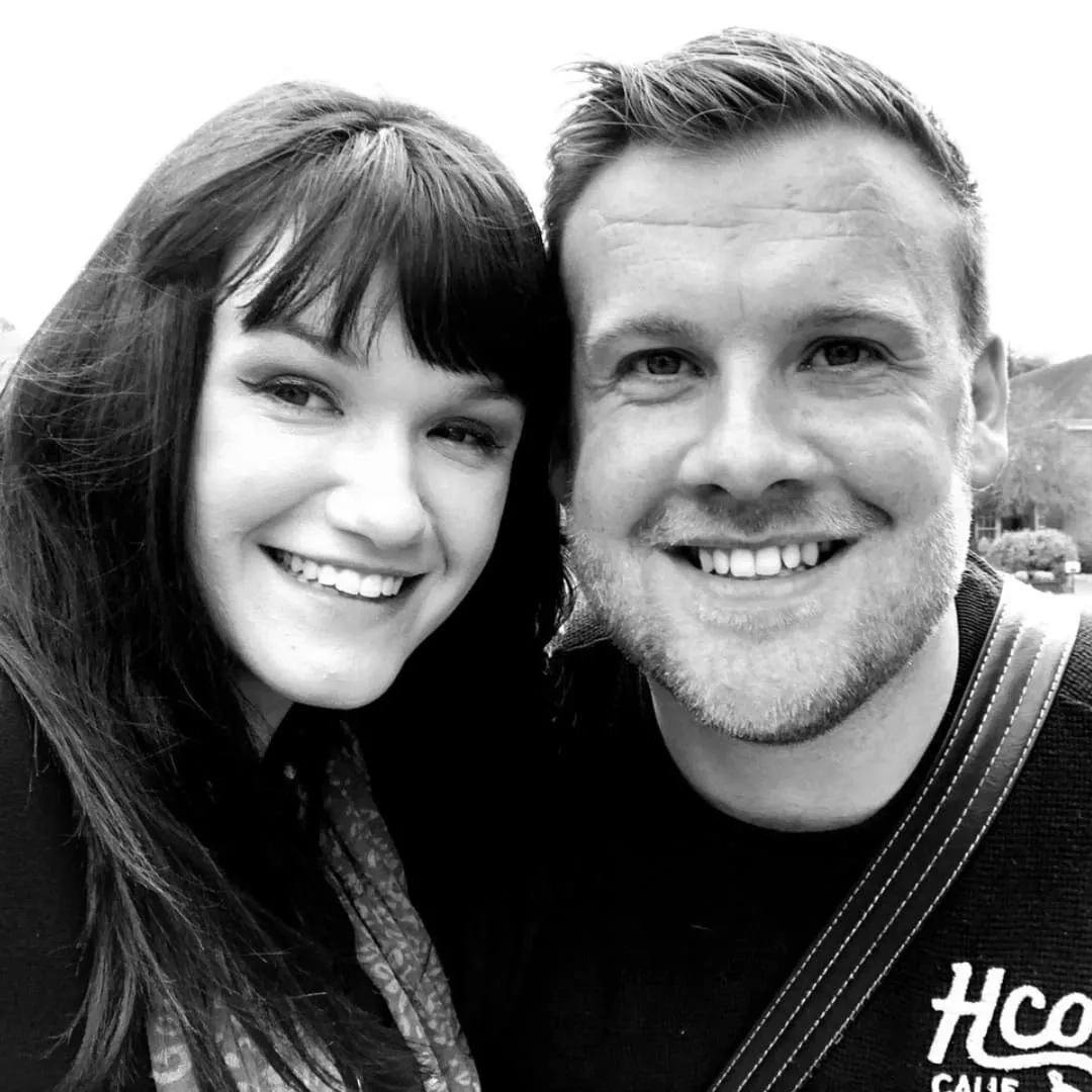 Sam with a friend, smiling at the camera. The image is in black and white.