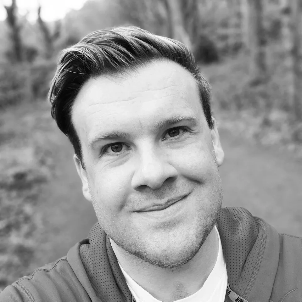 Sam taking a selfie while outdoors. He is smiling at the camera. The image is in black and white.