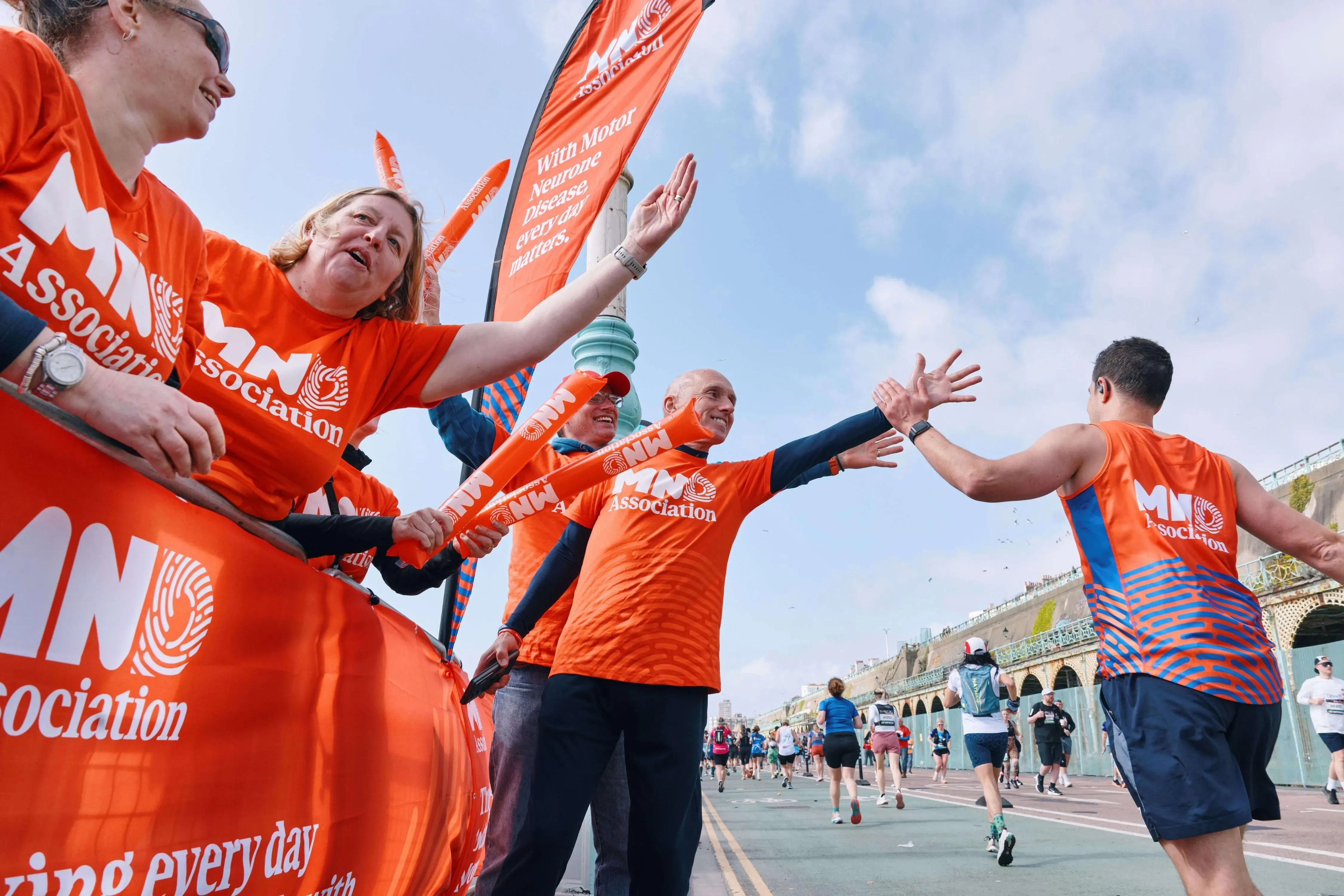 Marathon runner giving a high five to supporters all in MND tshirts